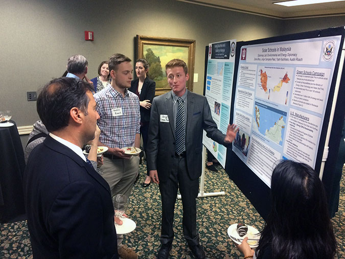 Student explaining research project to three others at a expo