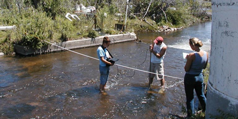 Students using equipment to perform research in a creek